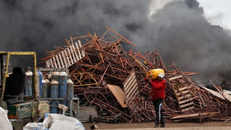 Работник бърза да изнесе бутилки с газ, които са използвали за рязане на металите.