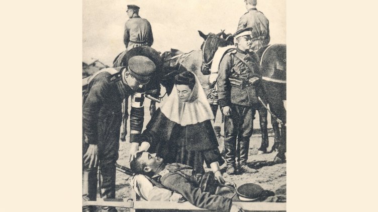 Елеонора фон Ройс-Кьостриц в самарянската форма, наведена към поставен в носилка ранен офицер на фронта.