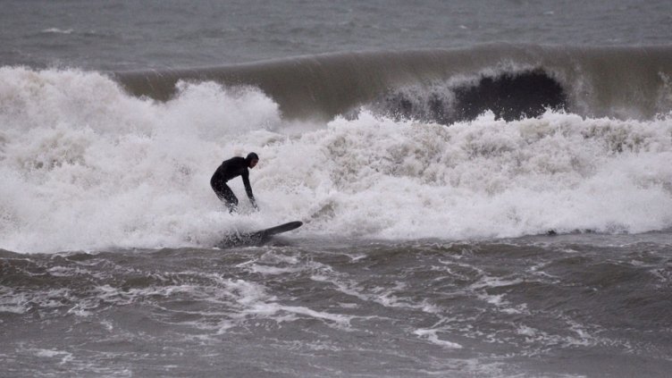 Смел мъж кара сърф в бурното море